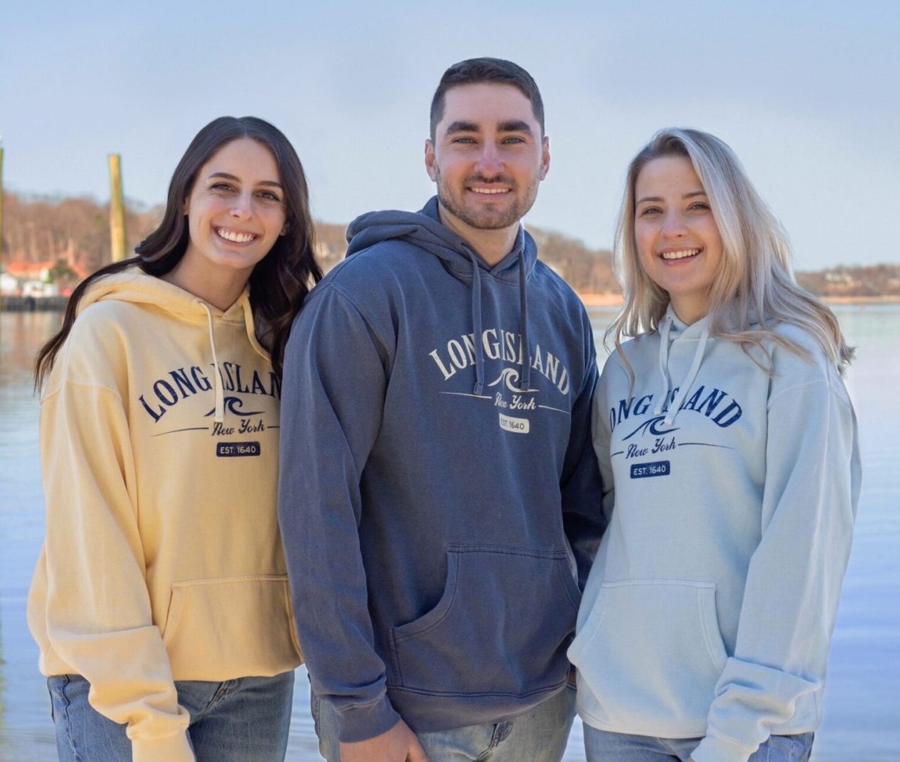 Three young adults wearing long island hoodies in yellow, steel blue and powder