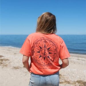 Person on beach wearing compass-print coral t-shirt
